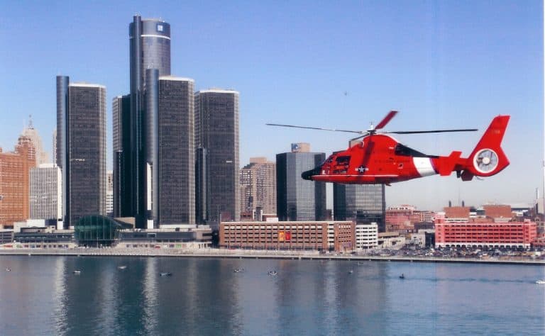 HH-65C "Dolphin" helicopter from Air Station Detroit over the Detroit River with the Renaissance Center and downtown Detroit in the background.